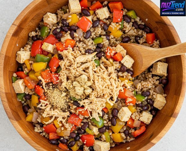Mixing quinoa, black beans, veggies, and spices in a bowl