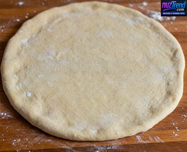 Rolling pizza dough into circular crust with rolling pin